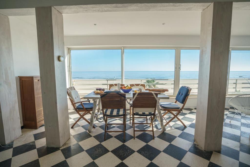 - une salle à manger avec une table et des chaises ainsi qu'une plage dans l'établissement Ô sable fin - Front de mer, à Canet