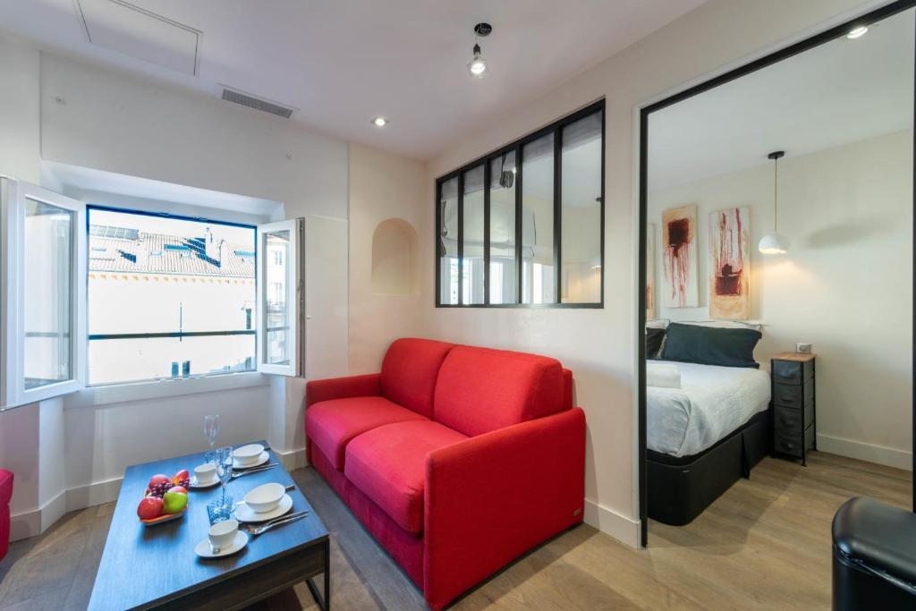 - un salon avec un canapé rouge et un lit dans l'établissement 1-Br Apartment with Air Conditioning Near La Croisette, à Cannes