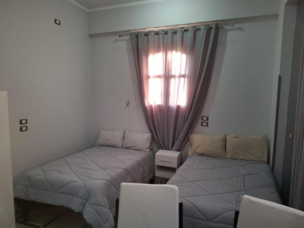 une chambre avec deux lits et une fenêtre dans l'établissement Ezba Guest House, à Louxor