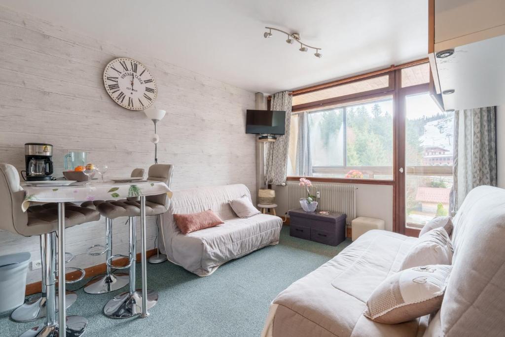 un salon avec un canapé et une horloge au mur dans l'établissement Belle Hutte - La Bresse montagne et parking privé, à La Bresse