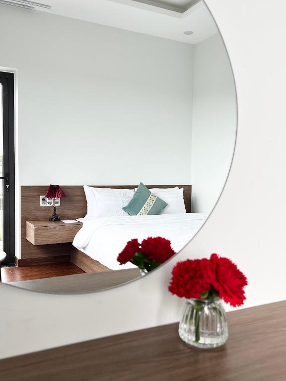 a bedroom with a mirror and a bed with red flowers at SAFFRON Dalat in Da Lat