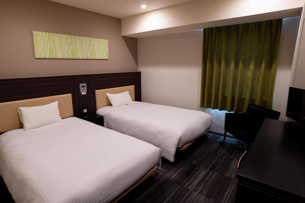 a hotel room with two beds and a window at Washington R&B Hotel Hachioji in Hachioji