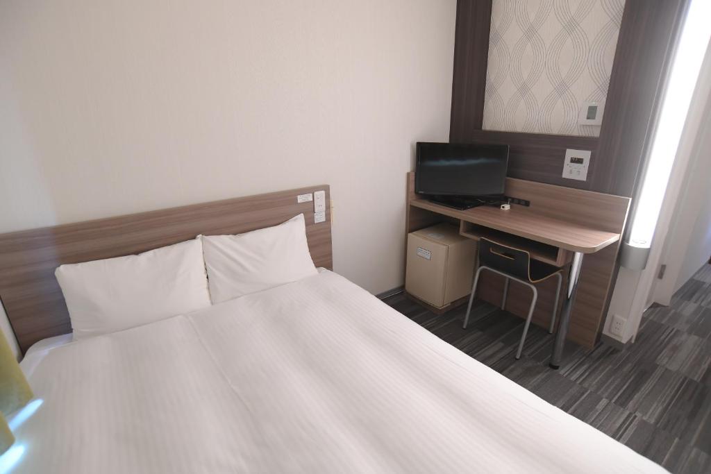 a bedroom with a bed and a desk with a computer at Washington R&B Hotel Hachioji in Hachioji
