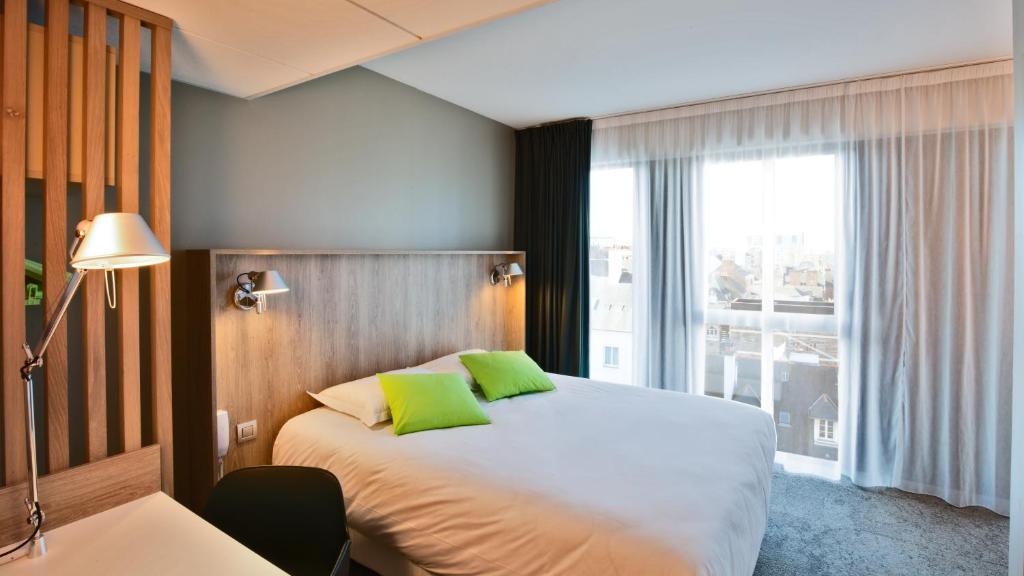 a hotel room with a bed and a large window at Campanile Rennes Centre - Gare in Rennes