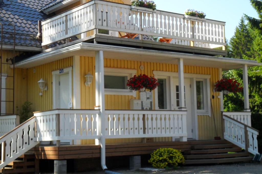 uma casa amarela com um deque branco e escadas em Laiskan Kartano em Härmä