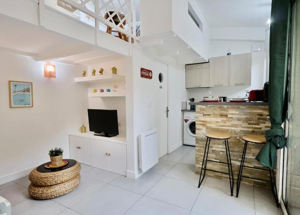 une cuisine avec des placards blancs, une table et un tabouret dans l'établissement Ancienne bâtisse en plein coeur du port avec clim, à Nice