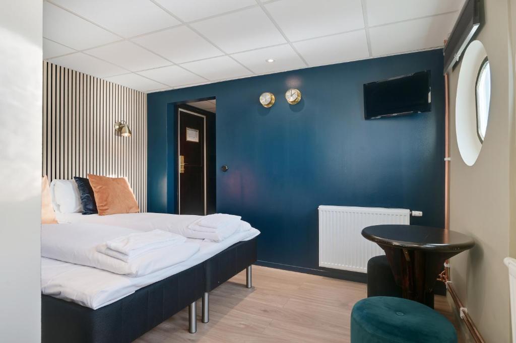 a room with a bed with a blue wall at Mälardrottningen Yacht Hotel in Stockholm