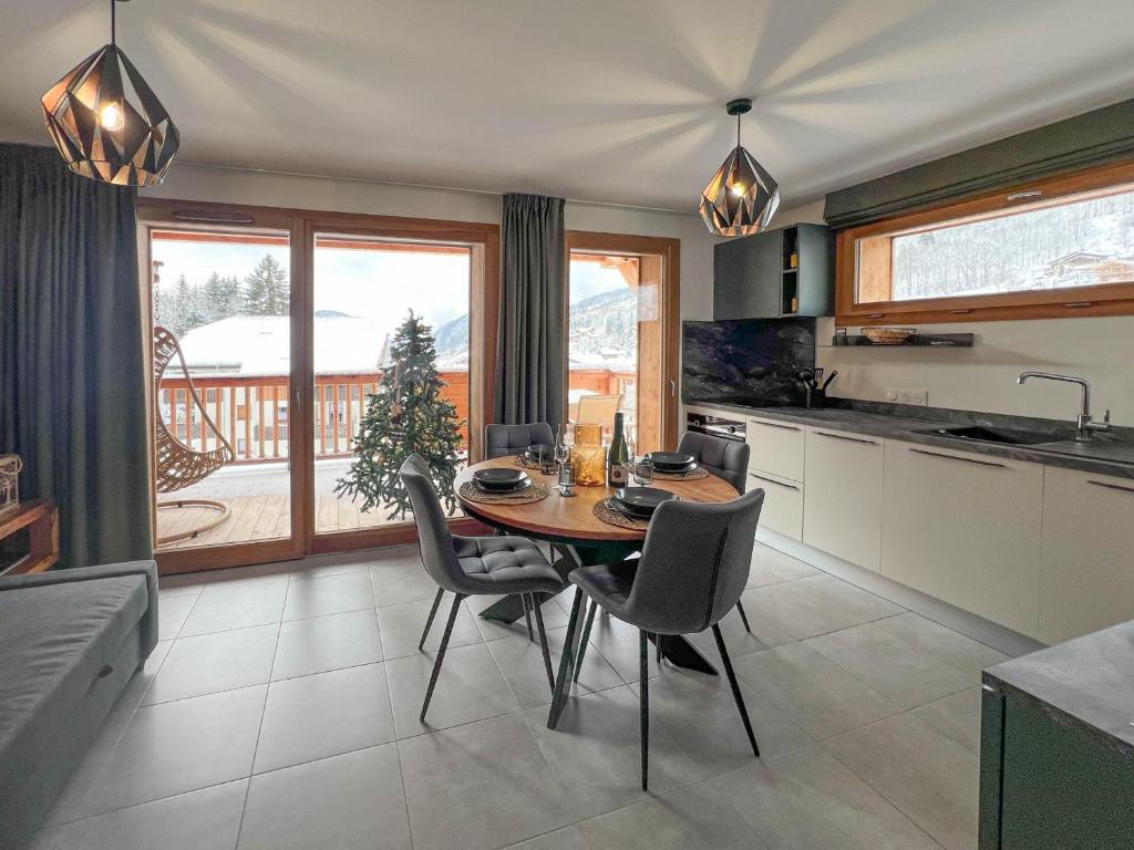 une cuisine avec une table et des chaises dans une cuisine dans l'établissement Les Gets: Appartement cosy, garage privé, Wi-Fi, linge inclus - FR-1-671-256, aux Gets