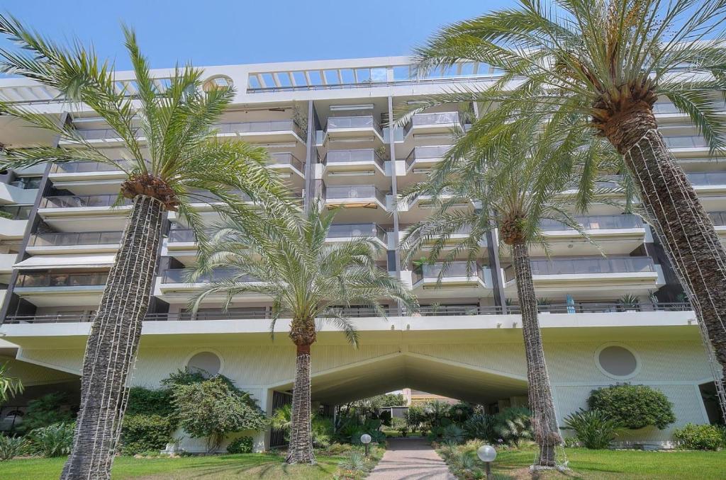 un bâtiment avec des palmiers devant dans l'établissement 1 Bedroom Apartment - Les Jardins de la Croisette, à Cannes