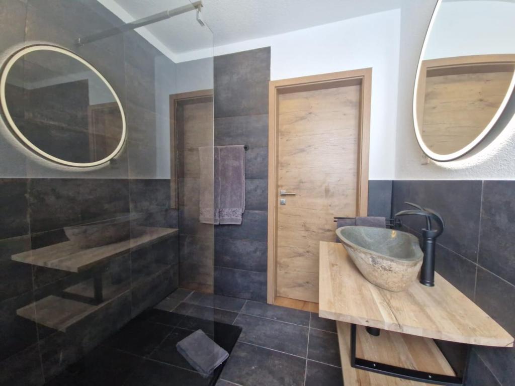 een badkamer met een bad, een wastafel en spiegels bij FeWo's und Apartment's Blaues Haus in Davos