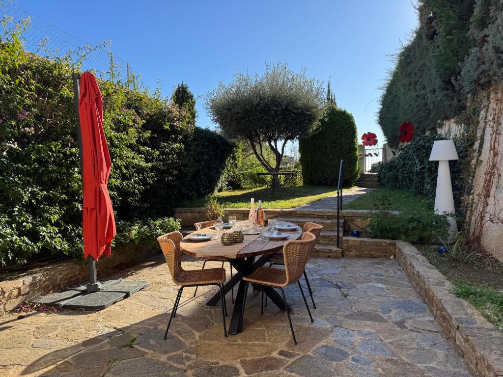 une table avec des chaises et un parasol sur une terrasse dans l'établissement L'écrin au Super Lavandou, au Lavandou