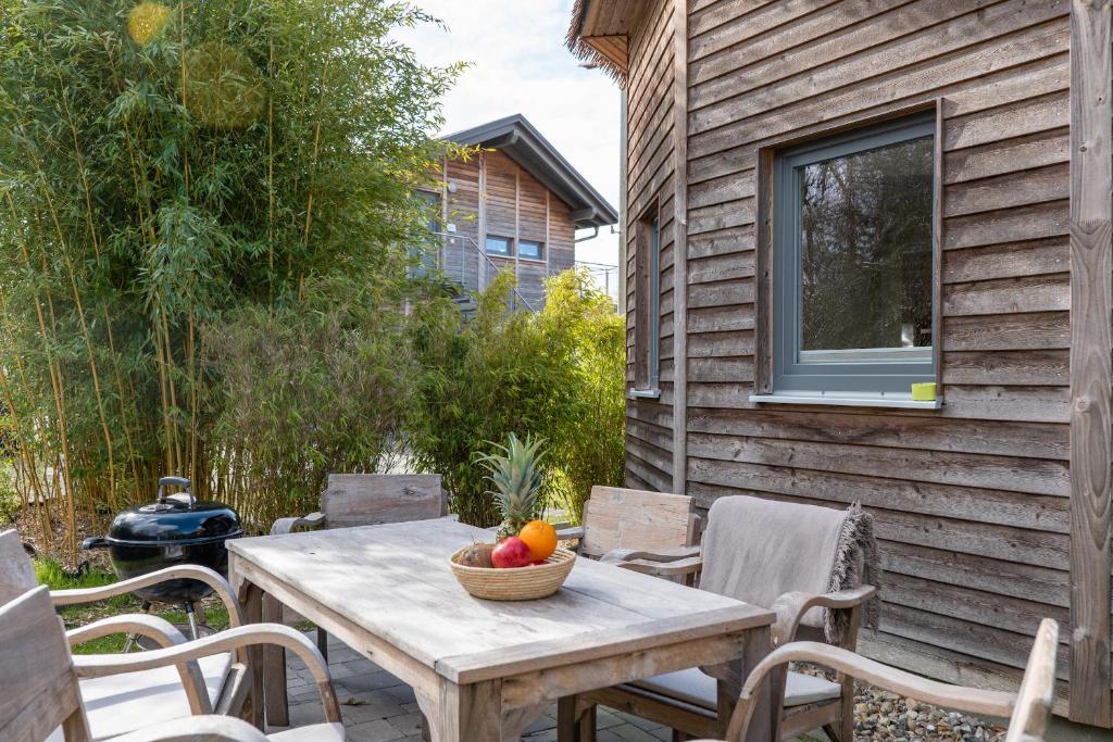 a wooden table with a bowl of fruit on a patio at Typ C1 Lodge - Napali Coast in Pelzerhaken
