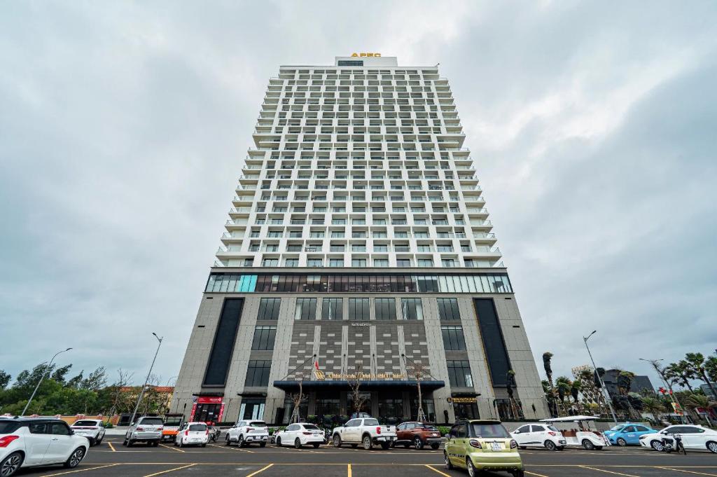 un edificio alto con auto parcheggiate in un parcheggio di HaNaLi - Apec Mandala Wyndham Phú Yên Condotel a Tuy Hoa