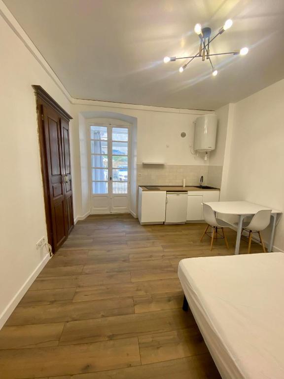 une grande chambre blanche avec une table et une cuisine dans l'établissement Charmant studio en centre-ville, à Corte