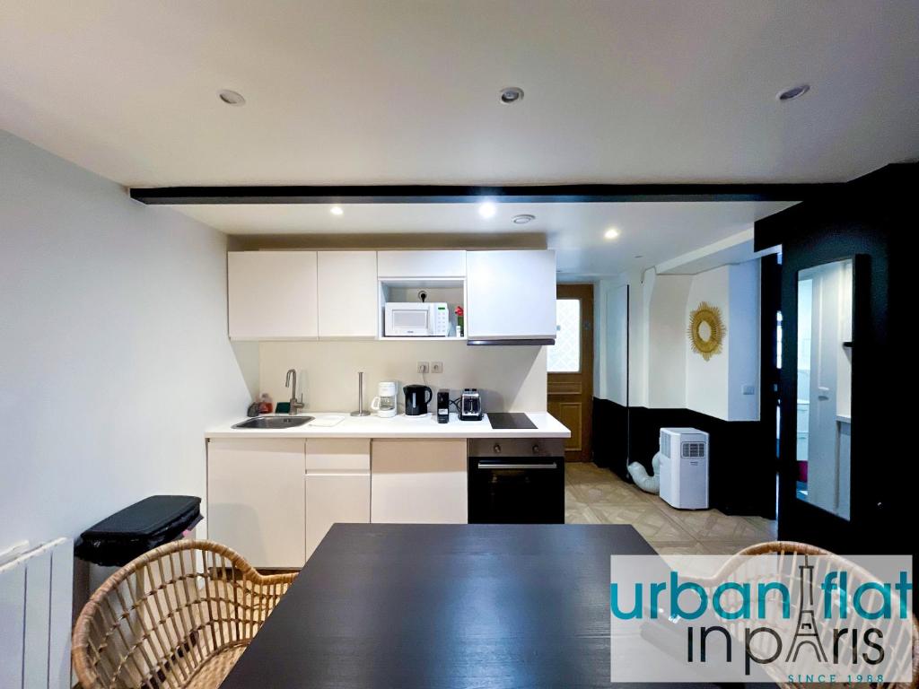 une cuisine avec des placards blancs et une table noire dans l'établissement 86 - Urban Charming Apartment, à Paris