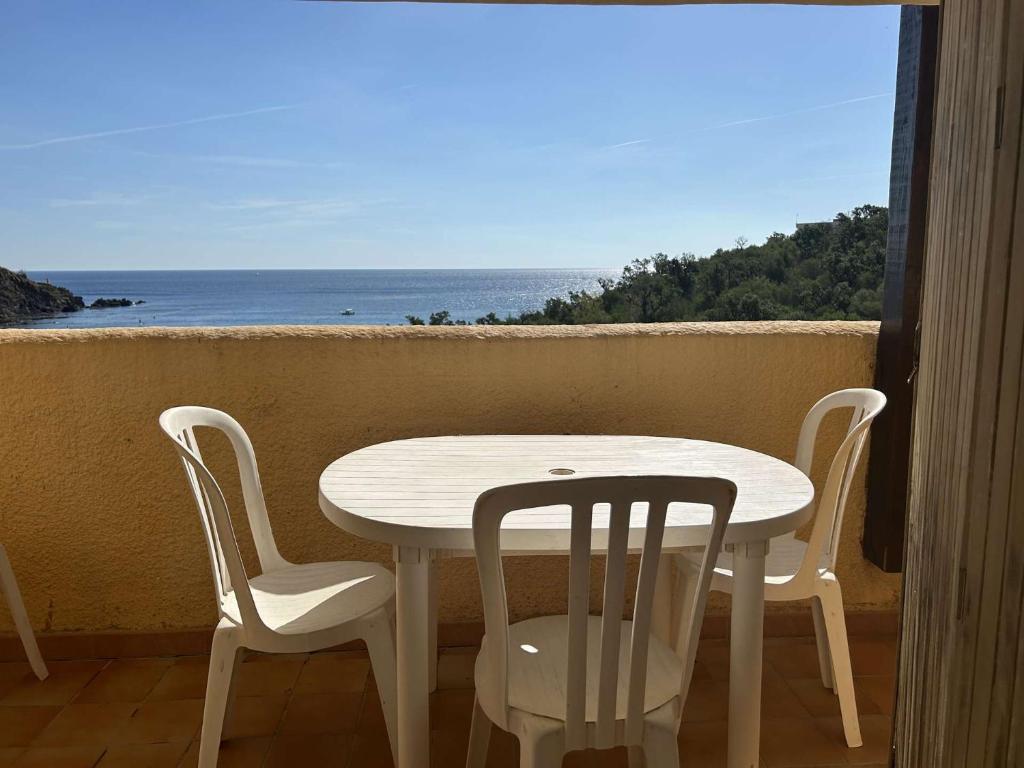 une table blanche et des chaises sur un balcon avec l'océan dans l'établissement Appart 2 pièces - cabine 4 couchages CERBERE BN200-951, à Cerbère
