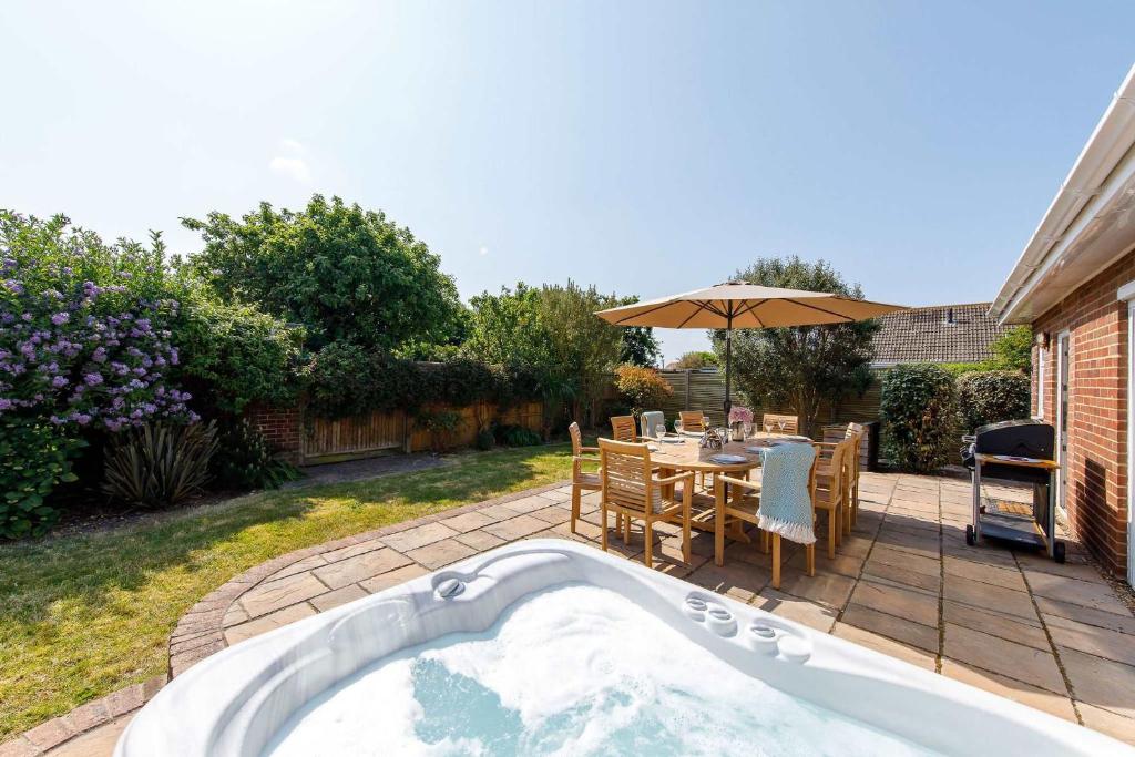 a hot tub in a backyard with a table and chairs at Beach house for 10 with hot tub & garden in West Wittering