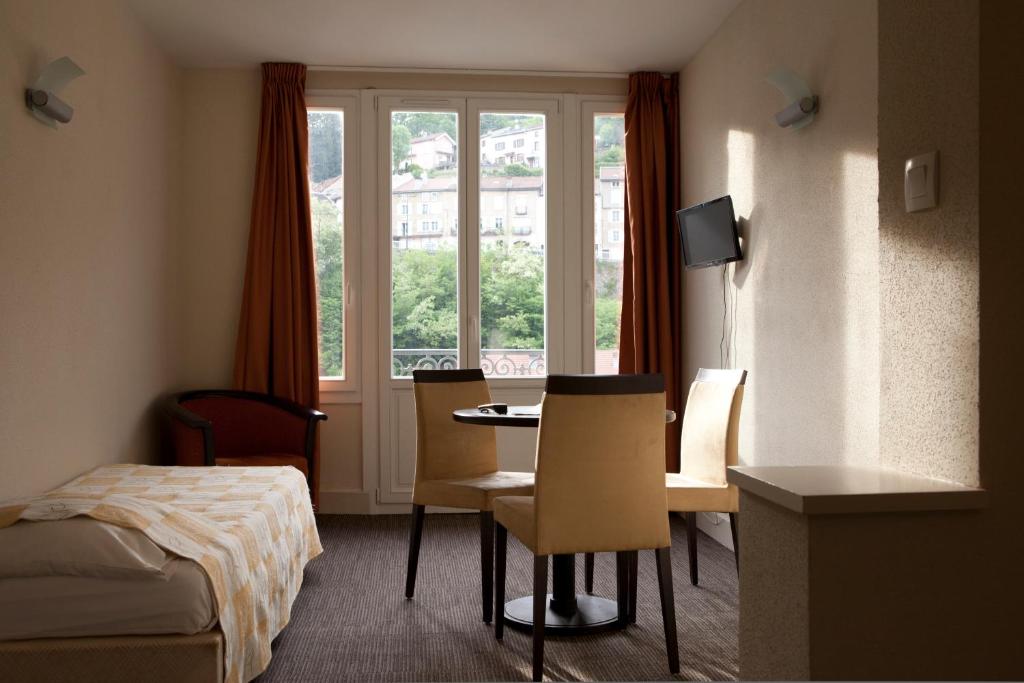 een hotelkamer met een bed en een tafel en stoelen bij Résidence Le Beauséjour by Popinns in Plombières-les-Bains