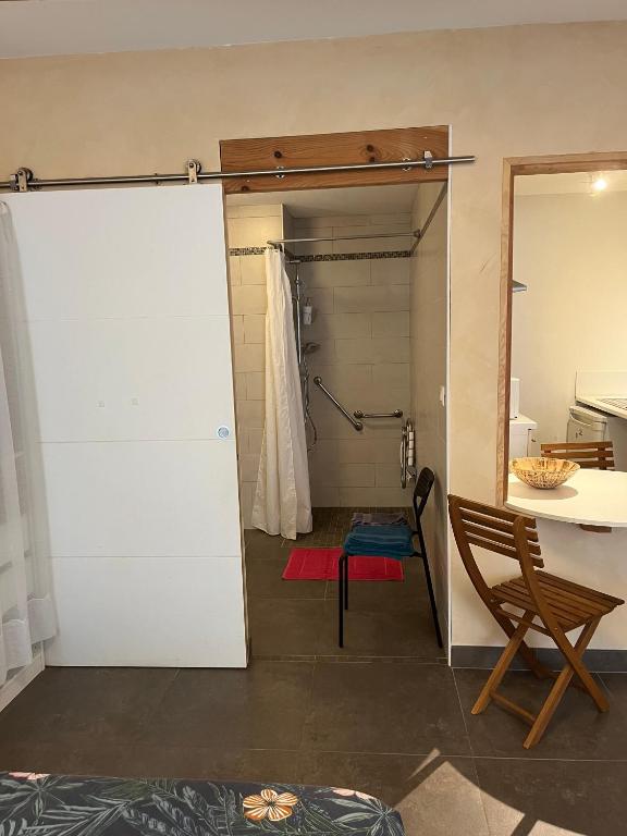 La salle de bains est pourvue d'une porte blanche et d'une table. dans l'établissement Studio 25m2 tout équipé Eauze, à Eauze