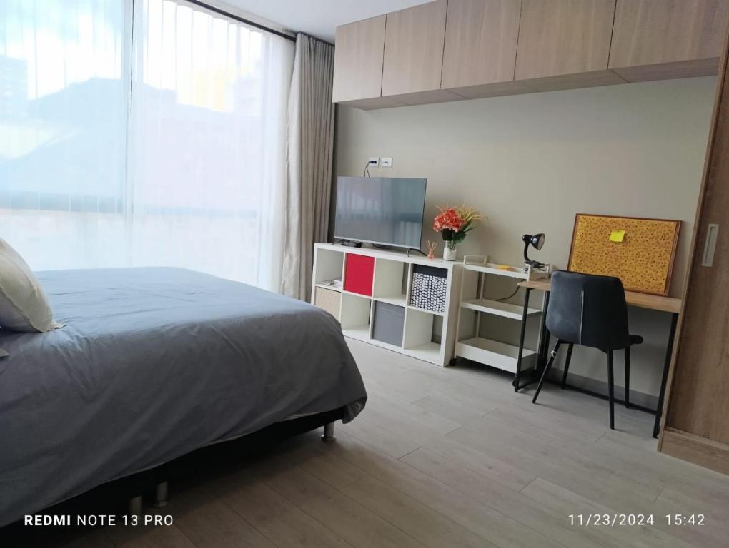 Un dormitorio con una cama y un escritorio con una computadora. en Apartaestudio Centro Bogotá, en Bogotá