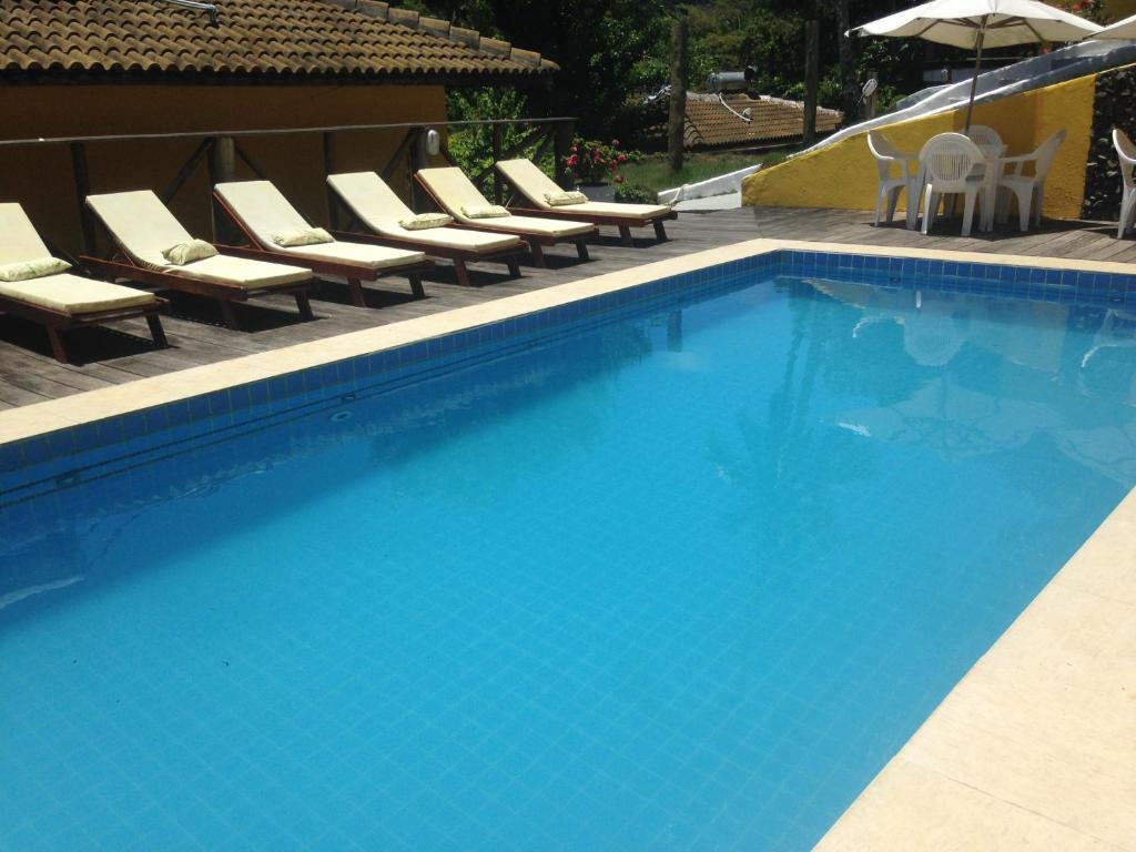a large swimming pool with chairs and an umbrella at Areia Branca Apart Hotel in Morro de São Paulo