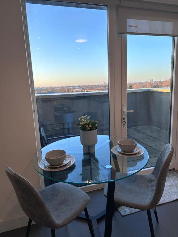 a glass dining room table with two chairs and a window at Beautiful 1 Bd Top floor Terraced Apartment in Barking
