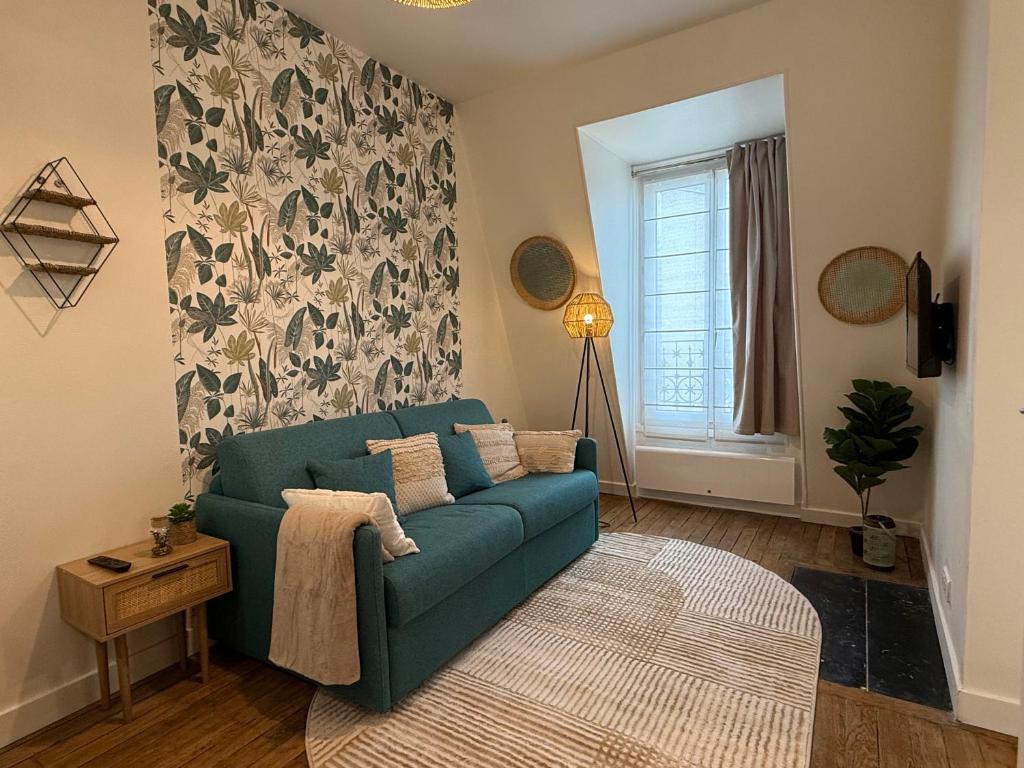 a living room with a green couch and a window at Le Petit Nid - cozy comfort close to Paris in Clichy