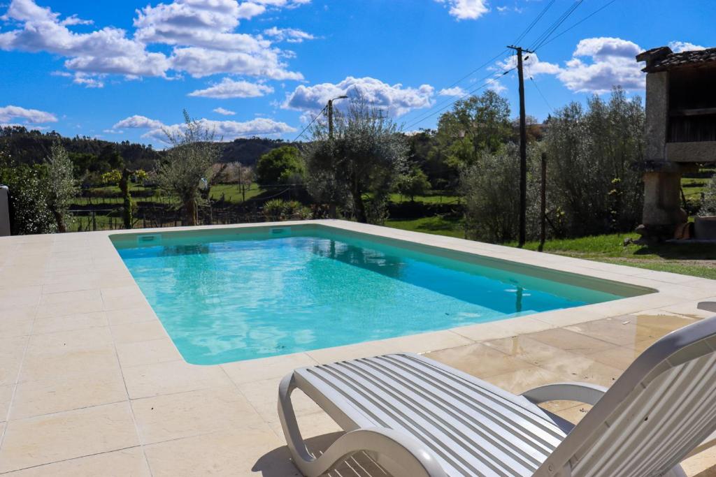 einen Pool mit einem Stuhl und einem Stuhl in der Unterkunft Casa da Laranjeira Turismo Rural by Gerês Casas in Vieira do Minho