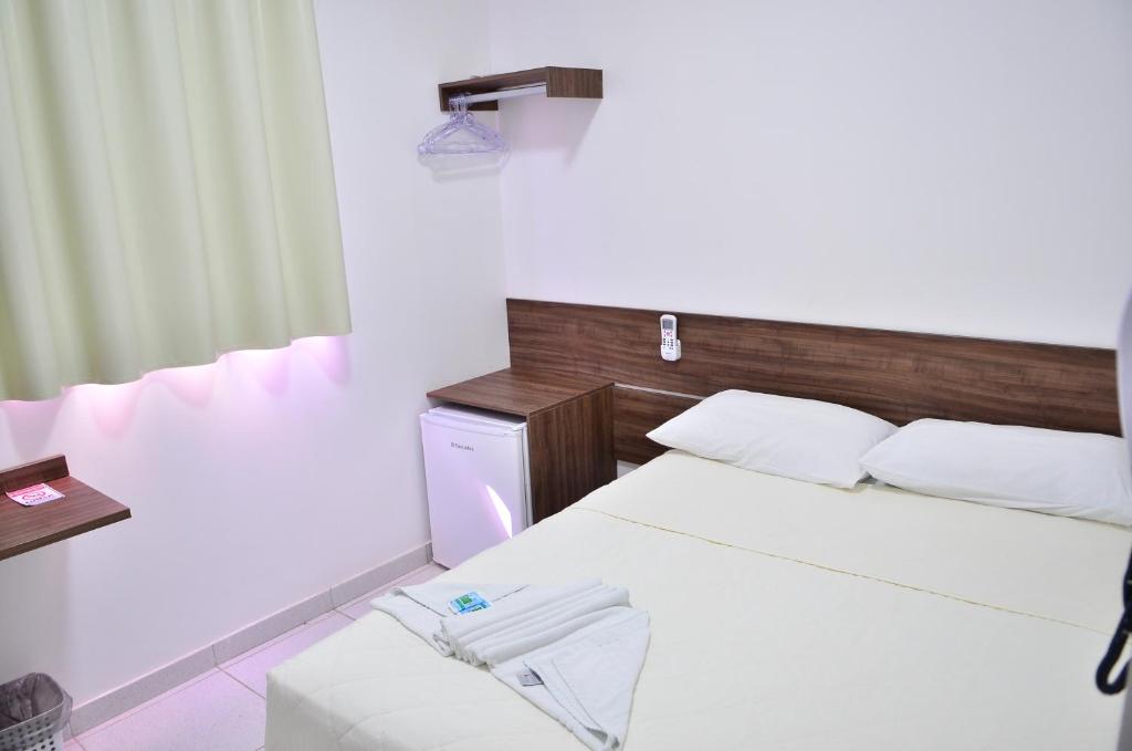 1 dormitorio con 1 cama, mesa y nevera en Hotel Norte en Macapá