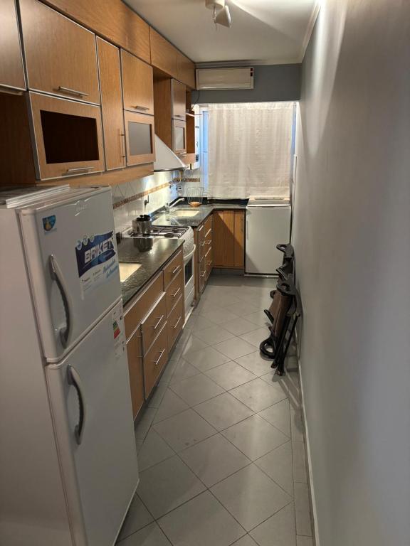 a kitchen with wooden cabinets and a white refrigerator at Departamento en Gualeguay in Gualeguay