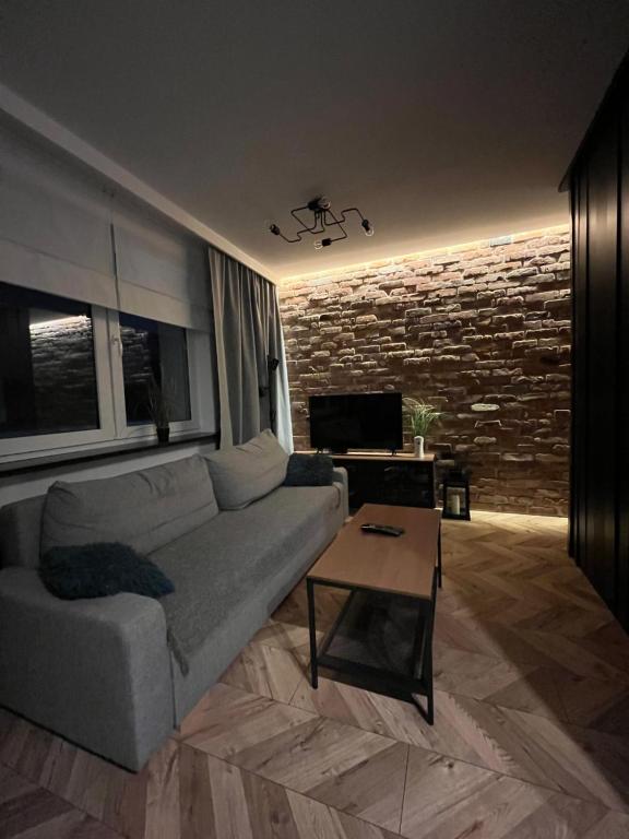 un salon avec un canapé et un mur de briques dans l'établissement Luksusowy loft nad jeziorem Swarzędz - Poznań TV wi-fi pralko-suszarka piekarnik, à Swarzędz