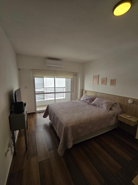 a bedroom with a bed and a desk and a window at Monumento y Río - Parking privado con costo adicional in Rosario