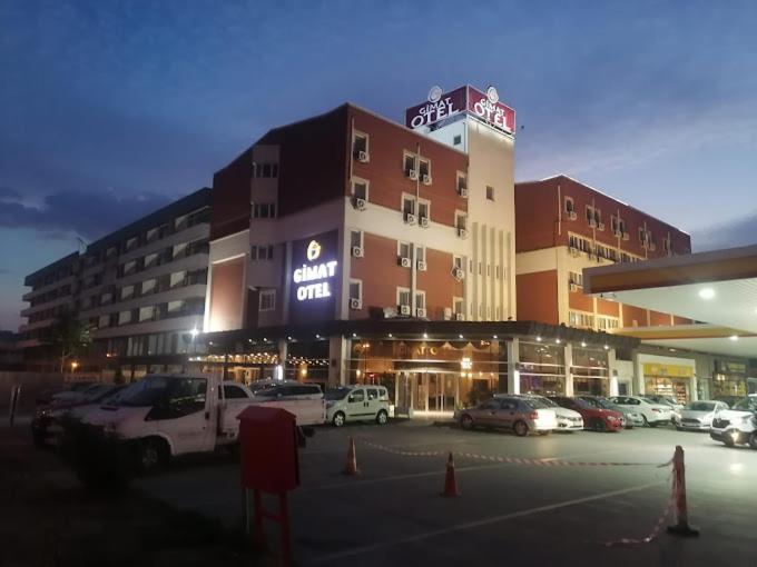 un grand bâtiment avec des voitures garées dans un parking dans l'établissement Gimat Otel, à Yenimahalle