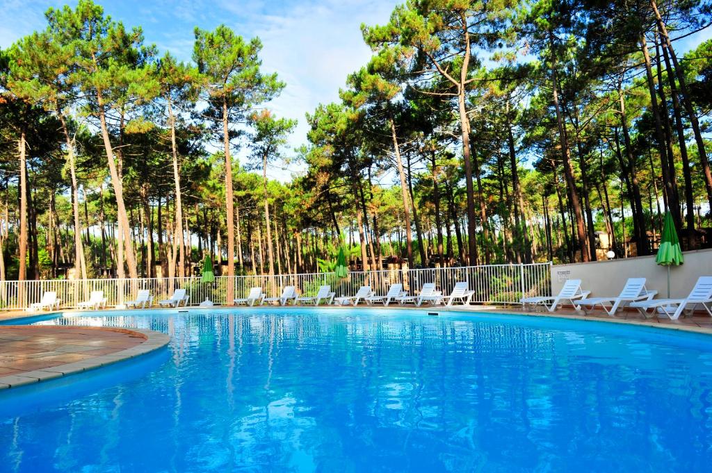 a large swimming pool with chairs and trees at VTF Les Bruyères in Maubuisson