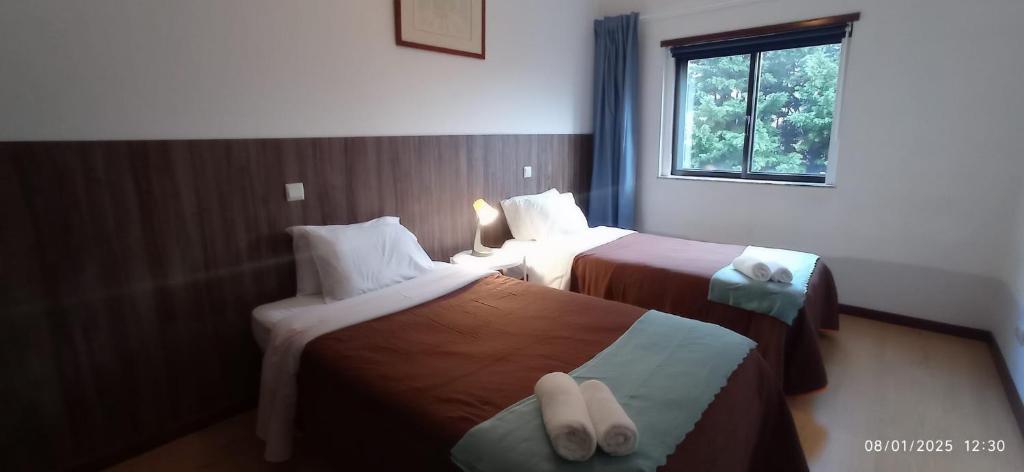 Una habitación de hotel con dos camas y una ventana. en APART Alojamentos Para Turismo e Negocios, en Braga