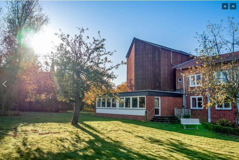 ein rotes Backsteinhaus mit einem Baum im Hof in der Unterkunft Gästehaus Bleckmar in Bergen
