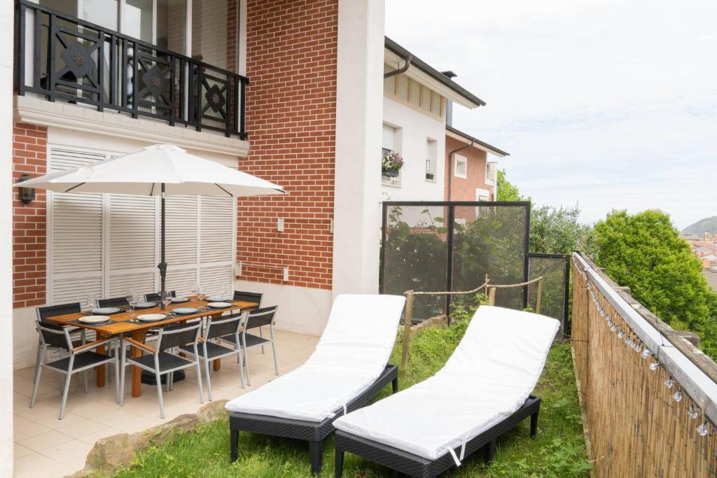 taras ze stołem, krzesłami i parasolem w obiekcie EARRA - Villa Eki - 2 garajes, playa a 7 min a pie w mieście Zarautz