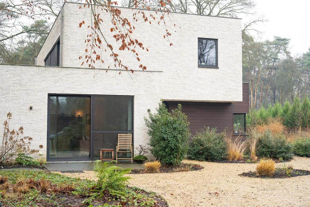 a house with a window and a chair in a yard at Studio Herman met buitenterras in Kapellenbos, bij de Kalmthoutse Heide in Kapellen