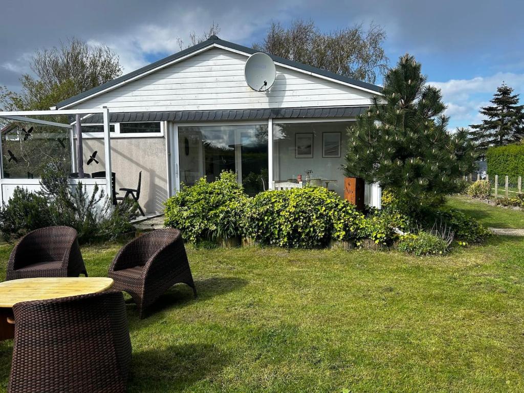 a house with a table and chairs in a yard at Buurman aan zee in Julianadorp