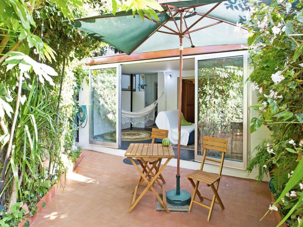um pátio com uma mesa, cadeiras e um guarda-sol em Apartment with Private Garden no Porto