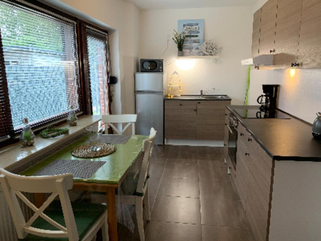 a kitchen with a table and a kitchen with a refrigerator at Gemütliche EG-Ferienwohnung Brazil mit eingezäunten Garten in Aurich