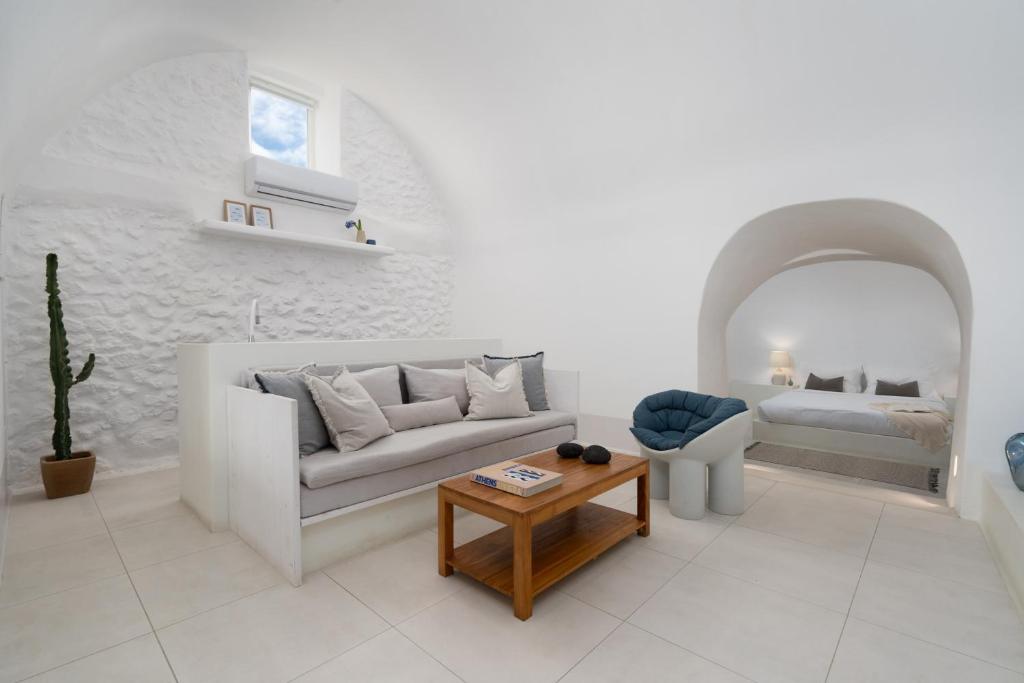 a white living room with a couch and a table at Kalyva Cycladic house - Oia Santorini in Oia