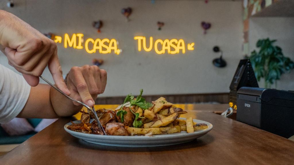 a person eating a plate of food with french fries at Viajero Cusco Hostel in Cusco