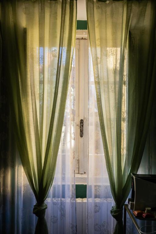 okno z zielonymi zasłonami przed nim w obiekcie La Foresteria di Palazzo Picedi Benettini w mieście Sarzana