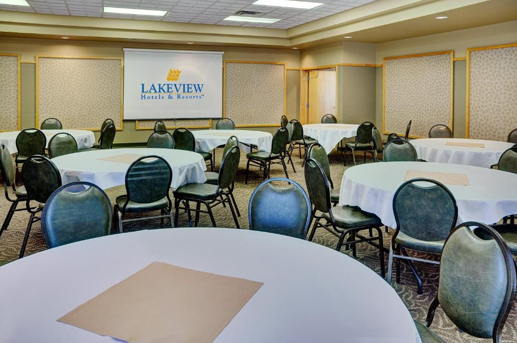 einen Konferenzraum mit Tischen, Stühlen und einem Bildschirm in der Unterkunft Lakeview Gimli Resort in Gimli