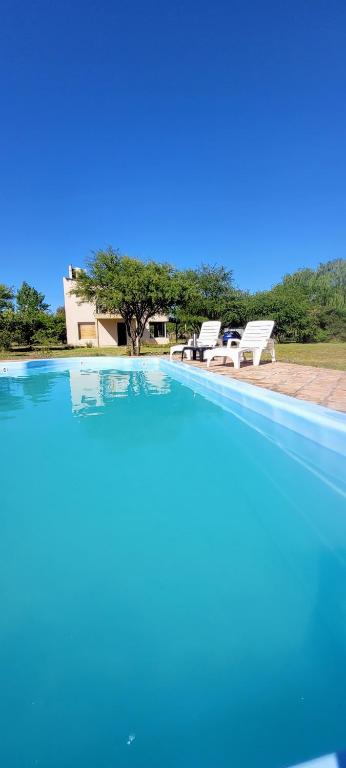 a large swimming pool with two chairs and a house at La Sietecolores in Toay
