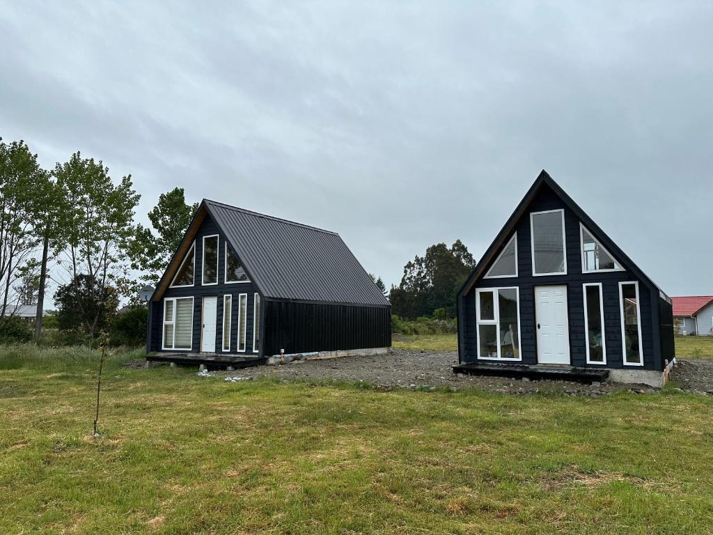 two black houses are sitting in a field at Cabañas RyL2 in Puerto Montt