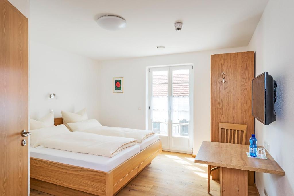 a bedroom with a bed and a table and a tv at Gästehaus Neubauer in Hörbach