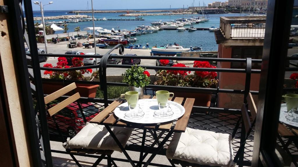 a table on a balcony with a view of a harbor at Aretè Guest House in Siracusa