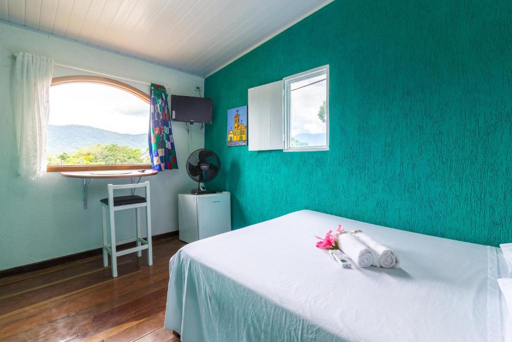 1 dormitorio con cama blanca y pared verde en SunriseBelaVista Pousada e Flats, en Paraty